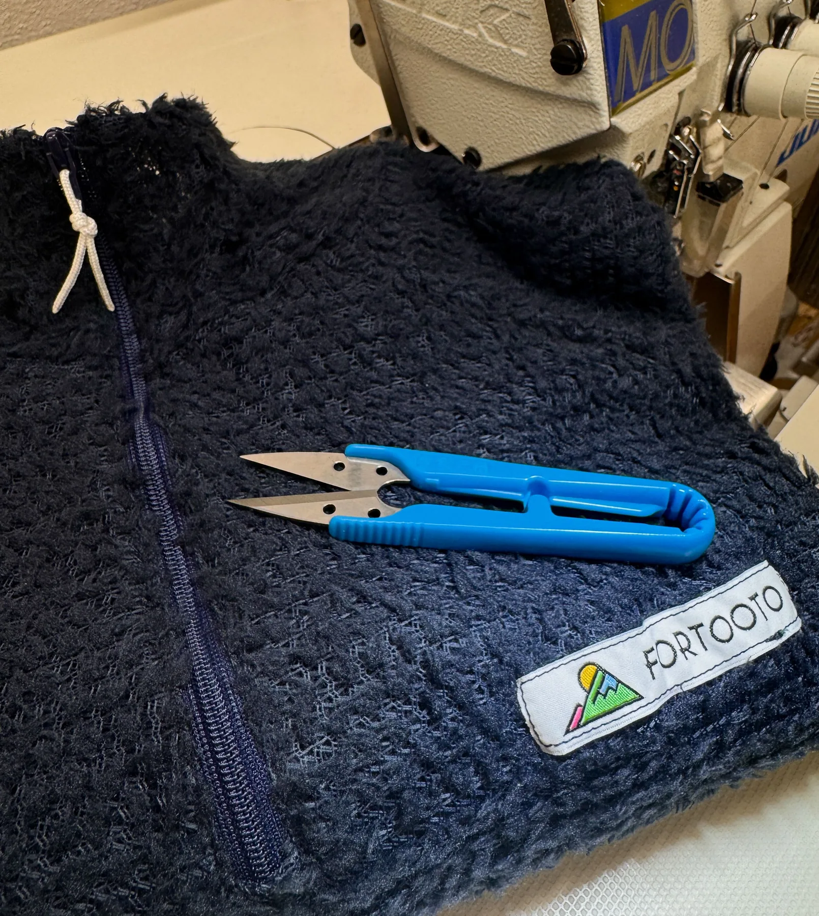 Making detail of Sparks Alpha 60 pullover with scissors and label